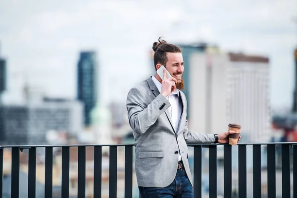 Młody biznesmen ze smartfonem stojąc na tarasie, dzięki czemu telefon. — Zdjęcie stockowe