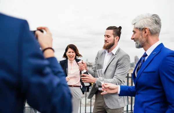 Een groep vrolijke zakenlui die een feestje hebben buiten op het dakterras in de stad. — Stockfoto