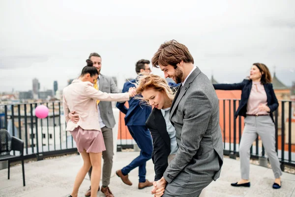 市内の屋上テラスで屋外でパーティーを開き、踊る楽しいビジネスマンのグループ. — ストック写真
