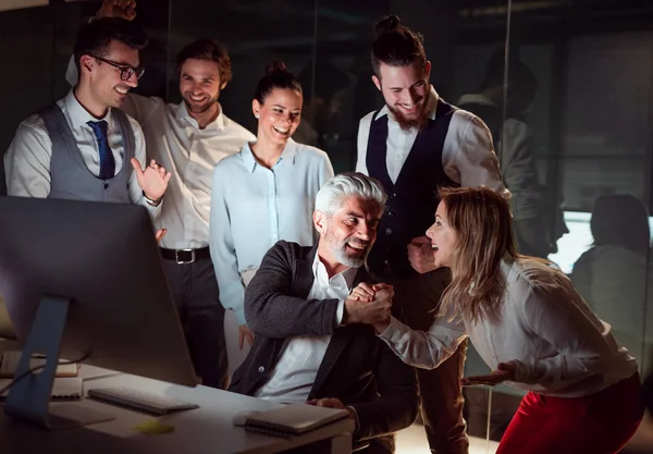 Un grupo de empresarios con ordenador en una oficina, expresando emoción . — Foto de Stock