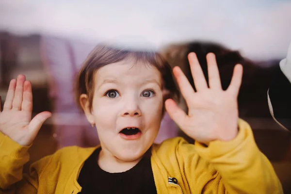 Um close-up de uma menina pequena olhando pela janela . — Fotografia de Stock