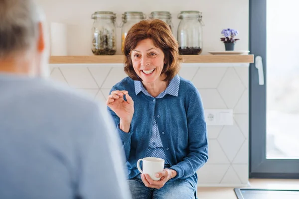 Un retrato de una pareja de ancianos en casa, hablando . — Foto de Stock