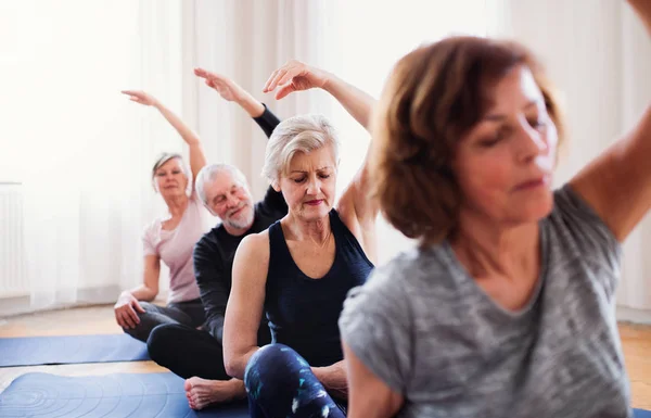 Gruppo di anziani che fanno esercizio di yoga nel club del centro sociale . — Foto Stock