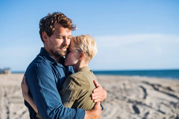 Unga par står utomhus på stranden och kramas. Kopiera utrymme. — Stockfoto