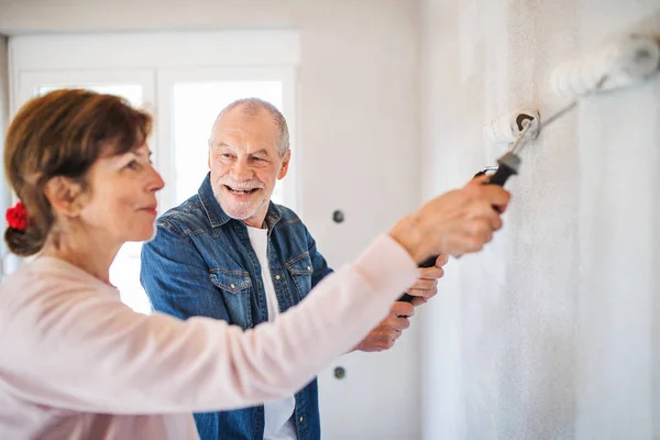 Senior coppia pittura pareti in nuova casa, concetto di trasferimento . — Foto Stock