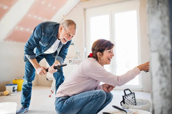 Couple sénior peignant des murs dans une nouvelle maison, concept de déménagement . — Photo