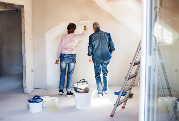 Vue arrière des murs de peinture de couple de personnes âgées dans la nouvelle maison, concept de déménagement . — Photo