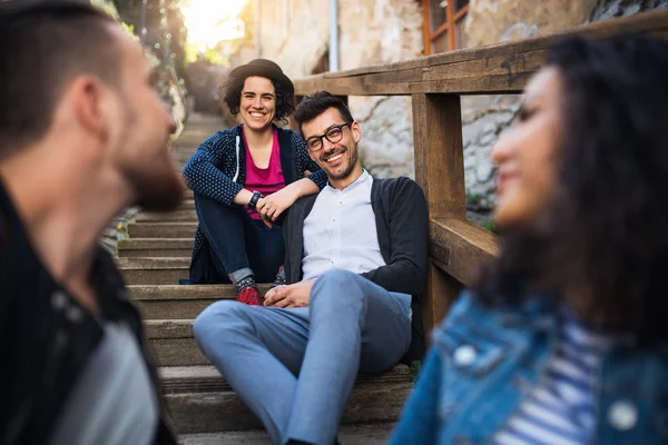 A portrait of group of young friends sitting outdoors on staircase in town. — Stock Photo, Image