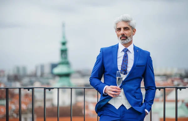 Un uomo d'affari maturo con vetro su una festa all'aperto sulla terrazza sul tetto della città . — Foto Stock