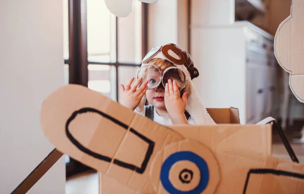 Een peuter jongen met kartonnen vliegtuig spelen binnenshuis thuis, Flying concept. — Stockfoto