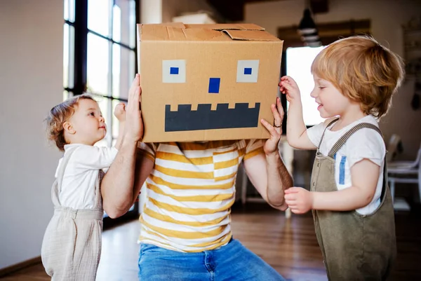 Dos niños pequeños con padre jugando adentro en casa . — Foto de Stock