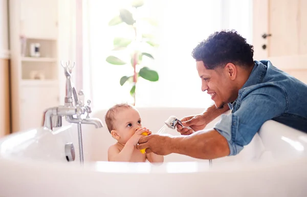Padre lavando pequeño hijo en un baño interior en casa . — Foto de Stock