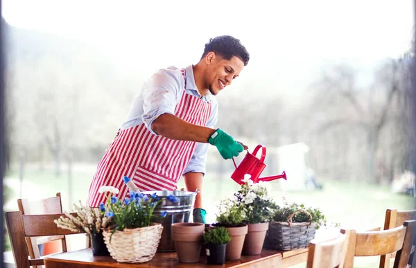 Um retrato do jovem jardineiro ao ar livre em casa, plantando flores . — Fotografia de Stock