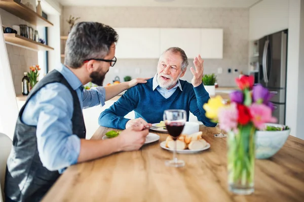 Un hijo hipster adulto y padre mayor en casa, comiendo almuerzo ligero . — Foto de Stock