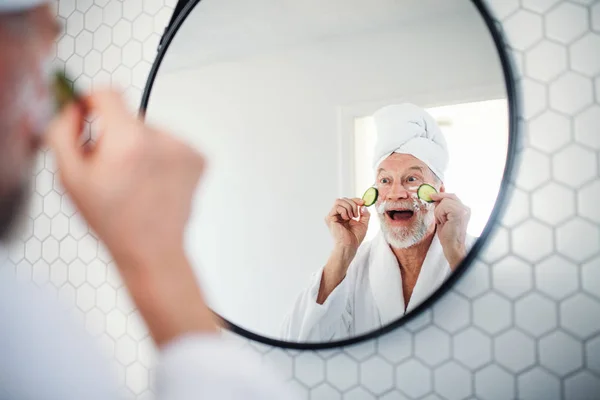 Ein älterer Herr mit Gurke auf den Augen zu Hause. Kopierraum. — Stockfoto