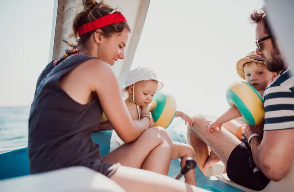 Padres con dos niños pequeños sentados en barco en vacaciones de verano . —  Fotos de Stock