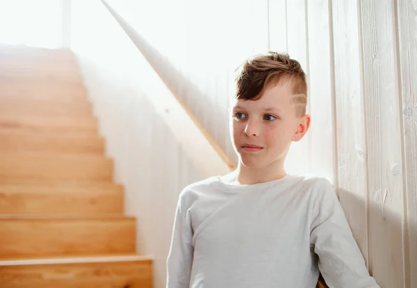 Un petit garçon debout à l'intérieur près des escaliers. Espace de copie . — Photo