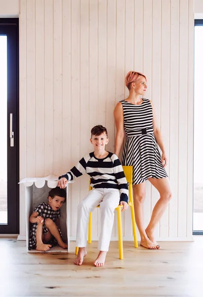 Vrouw met twee kinderen in zwart-wit kleding tegen witte houten muur. — Stockfoto