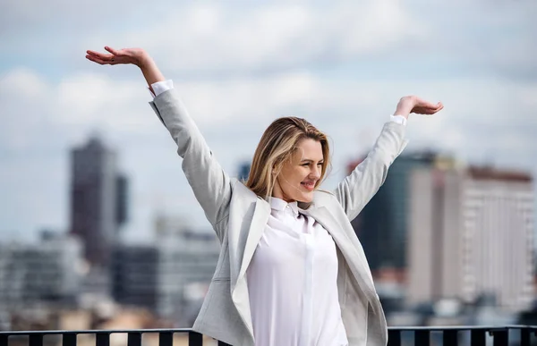 Una giovane donna d'affari in piedi su una terrazza, esprimendo eccitazione . — Foto Stock