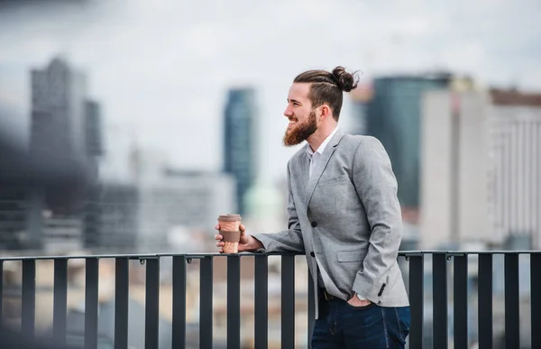 Un giovane uomo d'affari con caffè in piedi su una terrazza, a riposo . — Foto Stock