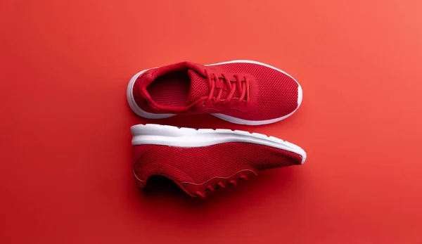 Una foto de estudio de un par de zapatillas de running sobre fondo rojo. Puesta plana . —  Fotos de Stock