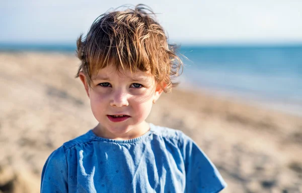 A portrait of small girl standing outdoors on sand beach. — Stock Photo, Image