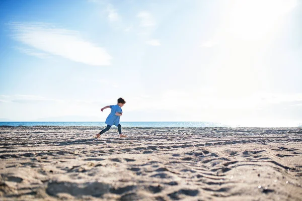 Seorang gadis kecil berjalan di luar ruangan di pantai pasir. Salin ruang . — Stok Foto