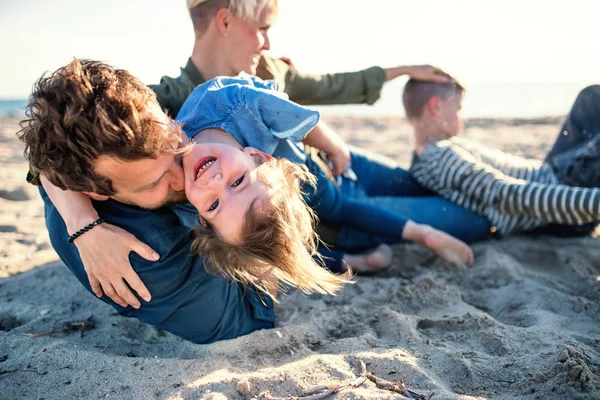 Familia joven con dos niños pequeños acostados al aire libre en la playa . — Foto de Stock