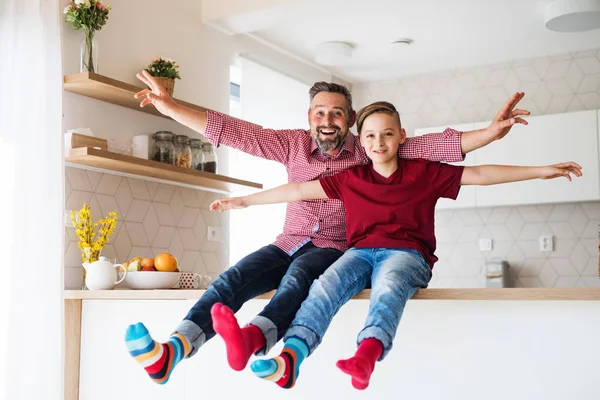 Ayah yang dewasa dengan anak kecil duduk di meja dapur di dalam ruangan, bersenang-senang . — Stok Foto