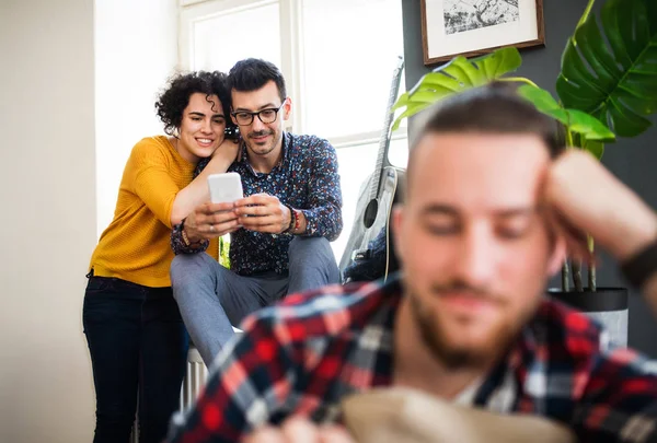 Kapalı kanepede oturan akıllı telefon ile genç arkadaş bir grup, ev paylaşım konsepti. — Stok fotoğraf