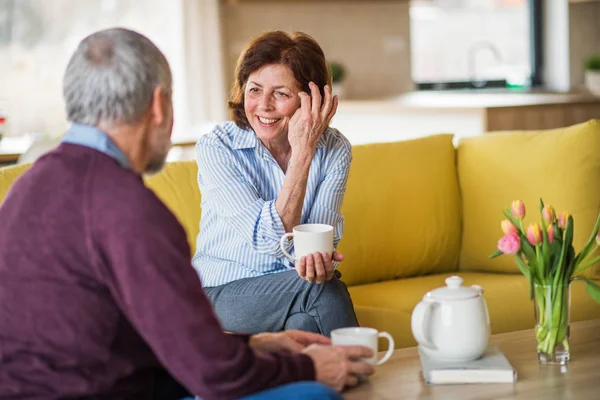 Affettuosa coppia di anziani innamorati seduti sul divano in casa, parlando . — Foto Stock