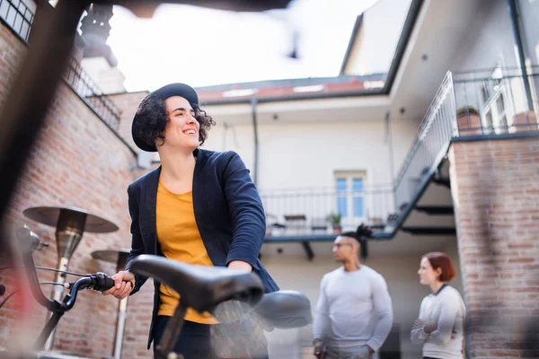 Una giovane donna d'affari felice con la bicicletta in piedi all'aperto . — Foto Stock