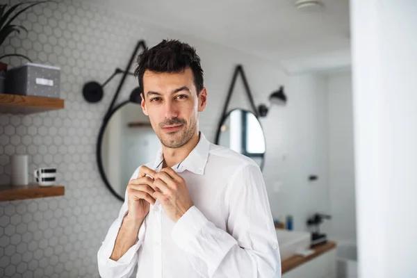 Joven vistiéndose de camisa en el baño por la mañana . — Foto de Stock