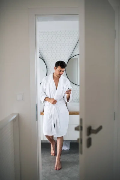 Jeune homme avec smartphone dans la salle de bain le matin . — Photo