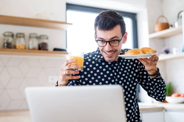 Ung man med frukost och laptop, ett hemmakontor koncept. — Stockfoto