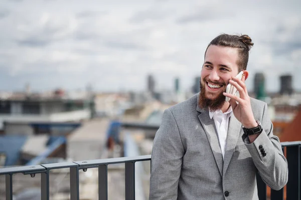 Bir odada telefon görüşmesi yapan, bir terasta akıllı telefon ile genç bir işadamı. — Stok fotoğraf