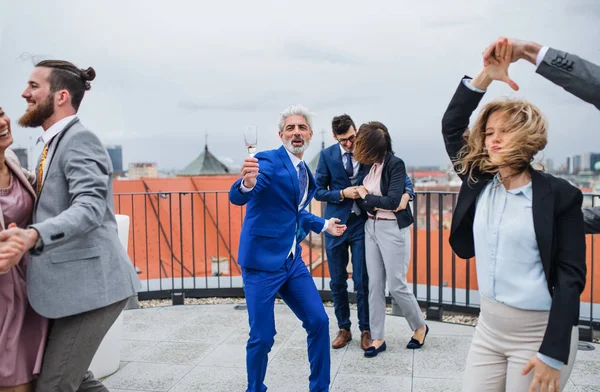 Un grupo de empresarios alegres haciendo una fiesta al aire libre en la azotea de la ciudad, bailando . —  Fotos de Stock