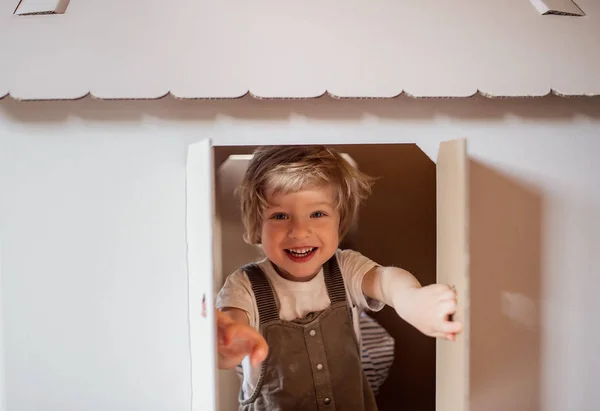 Un niño jugando adentro con casa de cartón en casa . — Foto de Stock