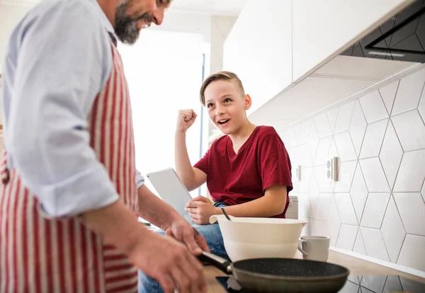 Mogen far med liten son inomhus i köket, gör pannkakor. — Stockfoto