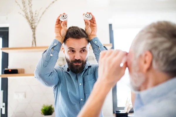 Adulto hipster filho e pai sênior em casa na cozinha, se divertindo . — Fotografia de Stock