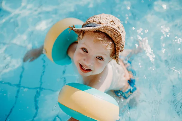 Ein kleiner Junge mit Armbinde schwimmt in den Sommerferien im Wasser. — Stockfoto