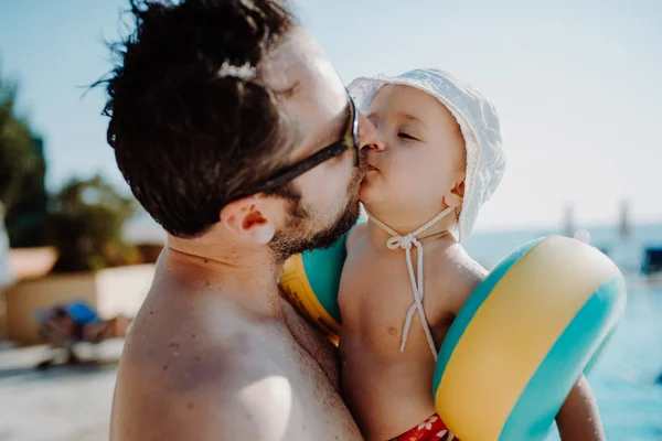여름 방학 에 수영장 옆에 서있는 완장을 가진 작은 아이를 가진 아버지. — 스톡 사진