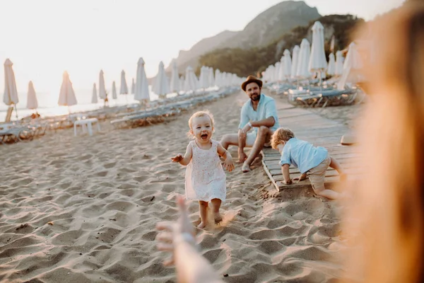 Giovane famiglia con bambini piccoli che si divertono sulla spiaggia in vacanza estiva . — Foto Stock