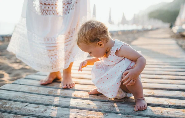 Midsection de madre joven con una niña en la playa en vacaciones de verano . — Foto de Stock