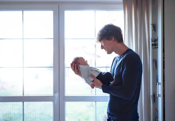 집에서 갓 태어난 아기를 안고 있는 젊은 아버지. 복사 공간. — 스톡 사진