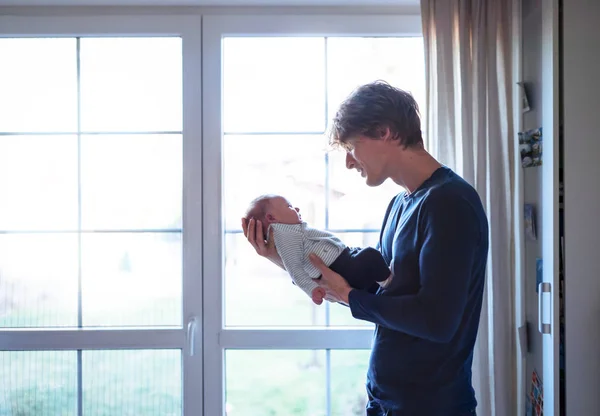 A young father holding a newborn baby at home. Copy space. — Stock Photo, Image