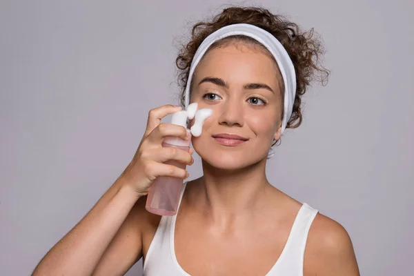 Portret van een jonge vrouw reinigen gezicht in een studio, schoonheid en huidverzorging. — Stockfoto