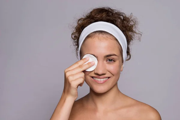 A portrait of a young woman cleaning face in a studio, beauty and skin care. — Stock Photo, Image