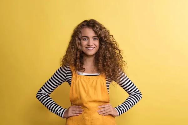 Porträt einer jungen Frau, die in einem Atelier vor gelbem Hintergrund steht. — Stockfoto