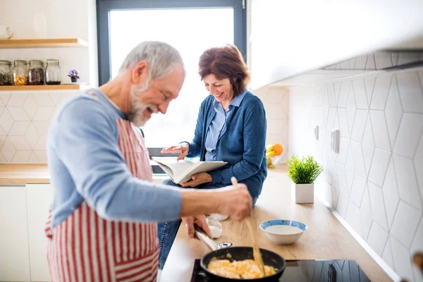 Ritratto di una coppia di anziani innamorati in casa, che cucina . — Foto Stock